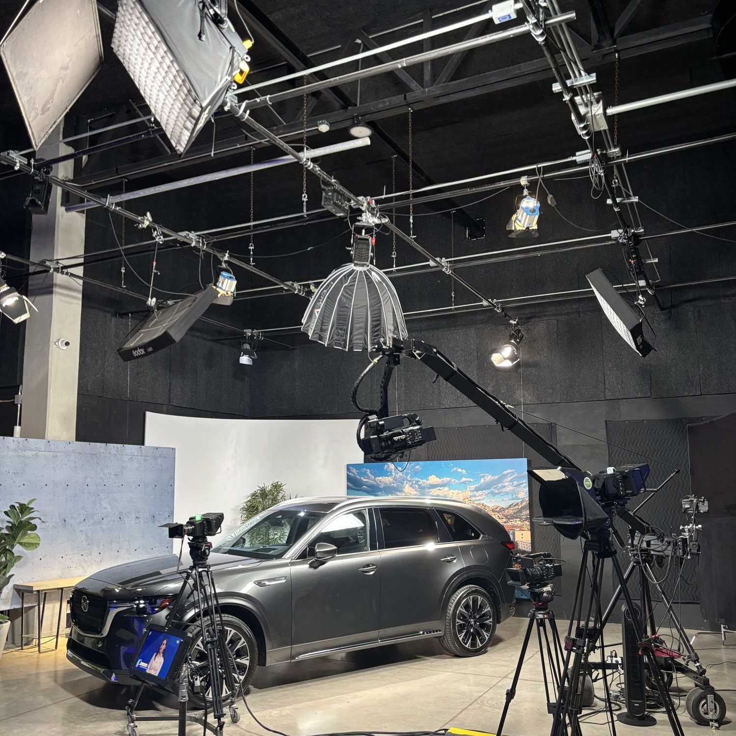 El set con grúa de cámara, estructura de iluminación y un auto en el estudio